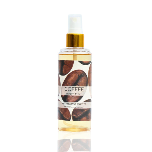 A bottle of Coffee Body Mist with a white label, gold cap, and coffee bean design.
