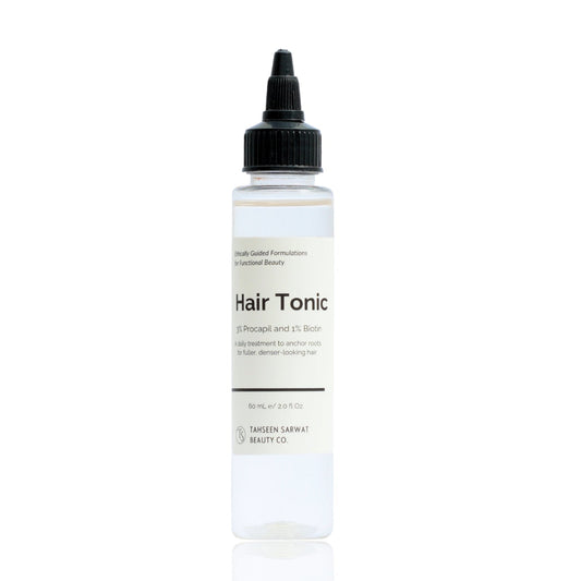A clear bottle with a black cap labeled as Hair Tonic, containing 100ml of liquid.