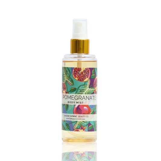 A clear spray bottle labeled Pomegranate Body Mist with a colorful label showing an image of a pomegranate and leaves.
