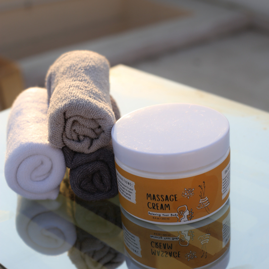 Massage Cream placed next to a lit candle, towel, and essential oils in a spa-like setting.