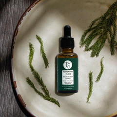 Bottle of Acneaway Elixir with green leaves on a ceramic plate