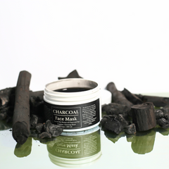 Charcoal Face Mask jar placed next to a brush applicator, towel, and natural ingredients like bamboo charcoal.
